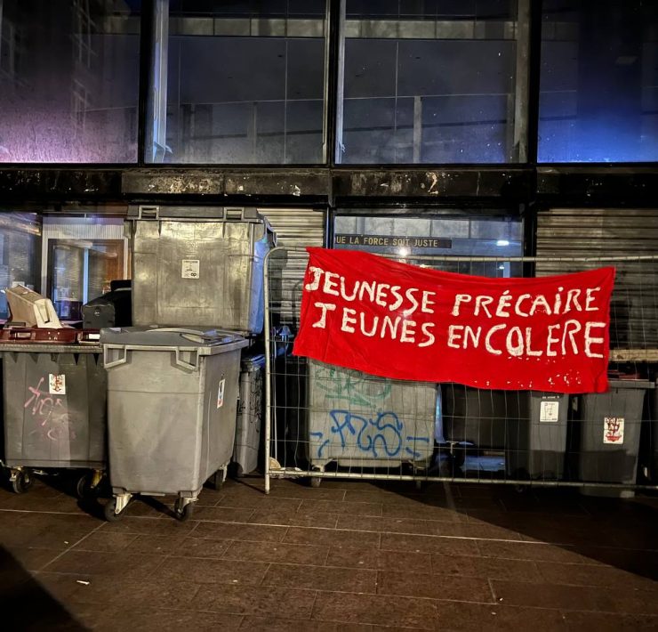 Des poubelles, une grille et une banderole placées devant le campus pour le bloquer © Vito Chollet